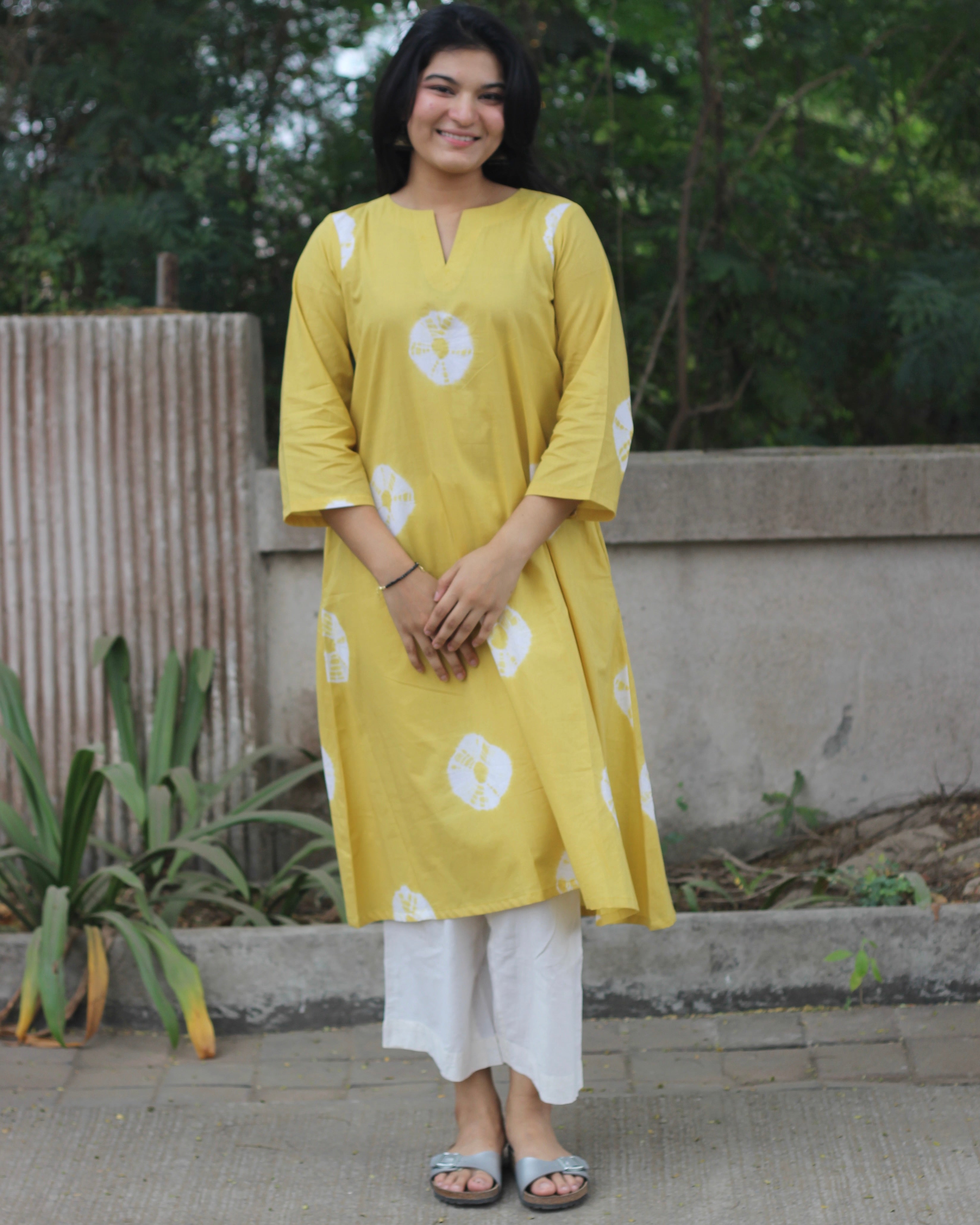 Yellow tie-dye cotton kurta with white bandhani print, V-neck, 3/4 sleeves, side pockets, and A-line design.