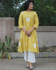 Yellow tie-dye cotton kurta with white bandhani print, V-neck, 3/4 sleeves, side pockets, and A-line design.