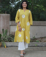 Yellow tie-dye cotton kurta with white bandhani print, V-neck, 3/4 sleeves, side pockets, and A-line design.