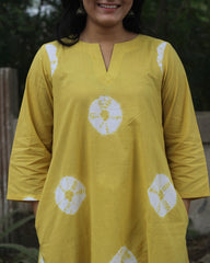 Yellow tie-dye cotton kurta with white bandhani print, V-neck, 3/4 sleeves, side pockets, and A-line design.