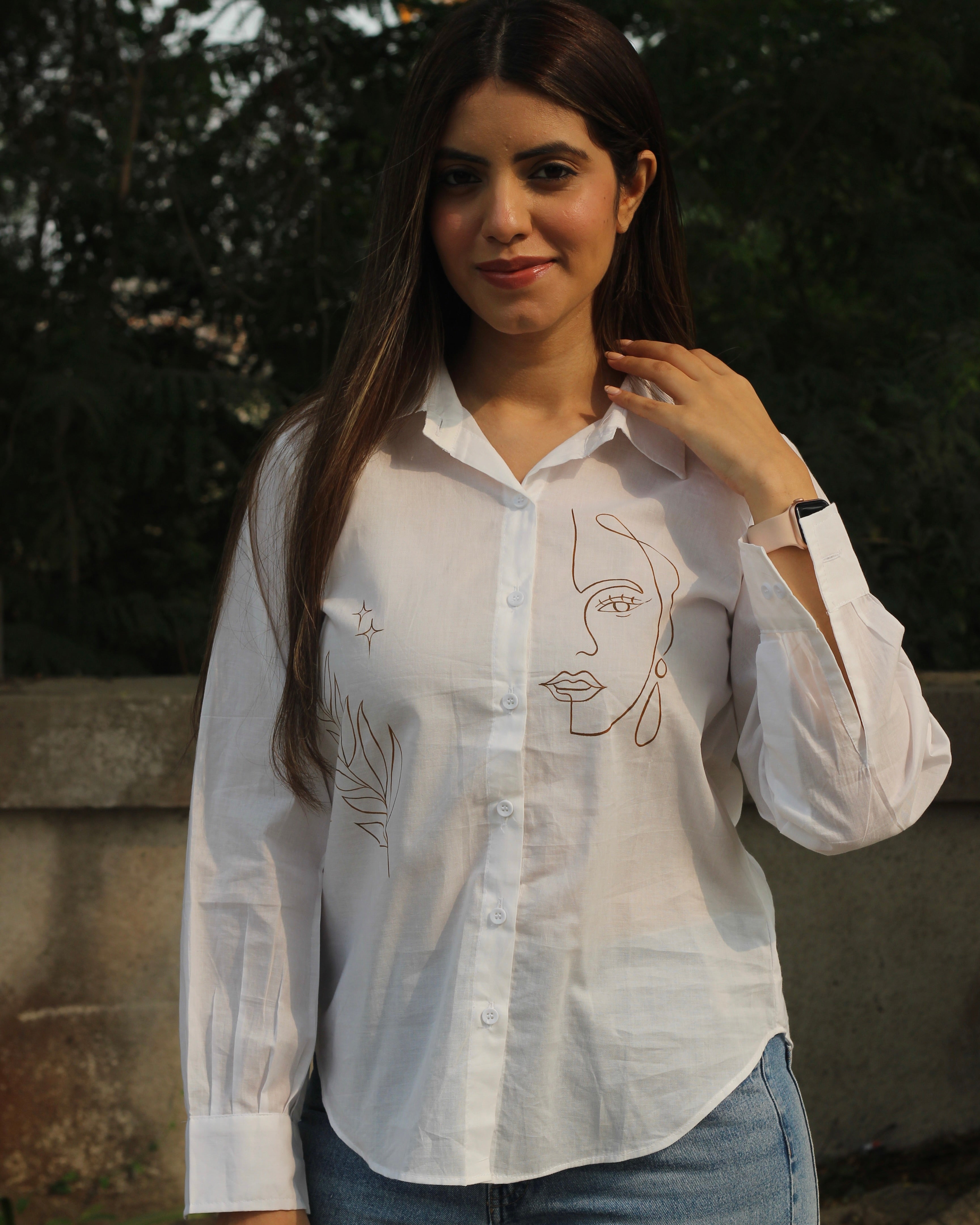 Hand-painted white shirt with bohemian brown leaf motifs, paired with jeans for a stylish look.