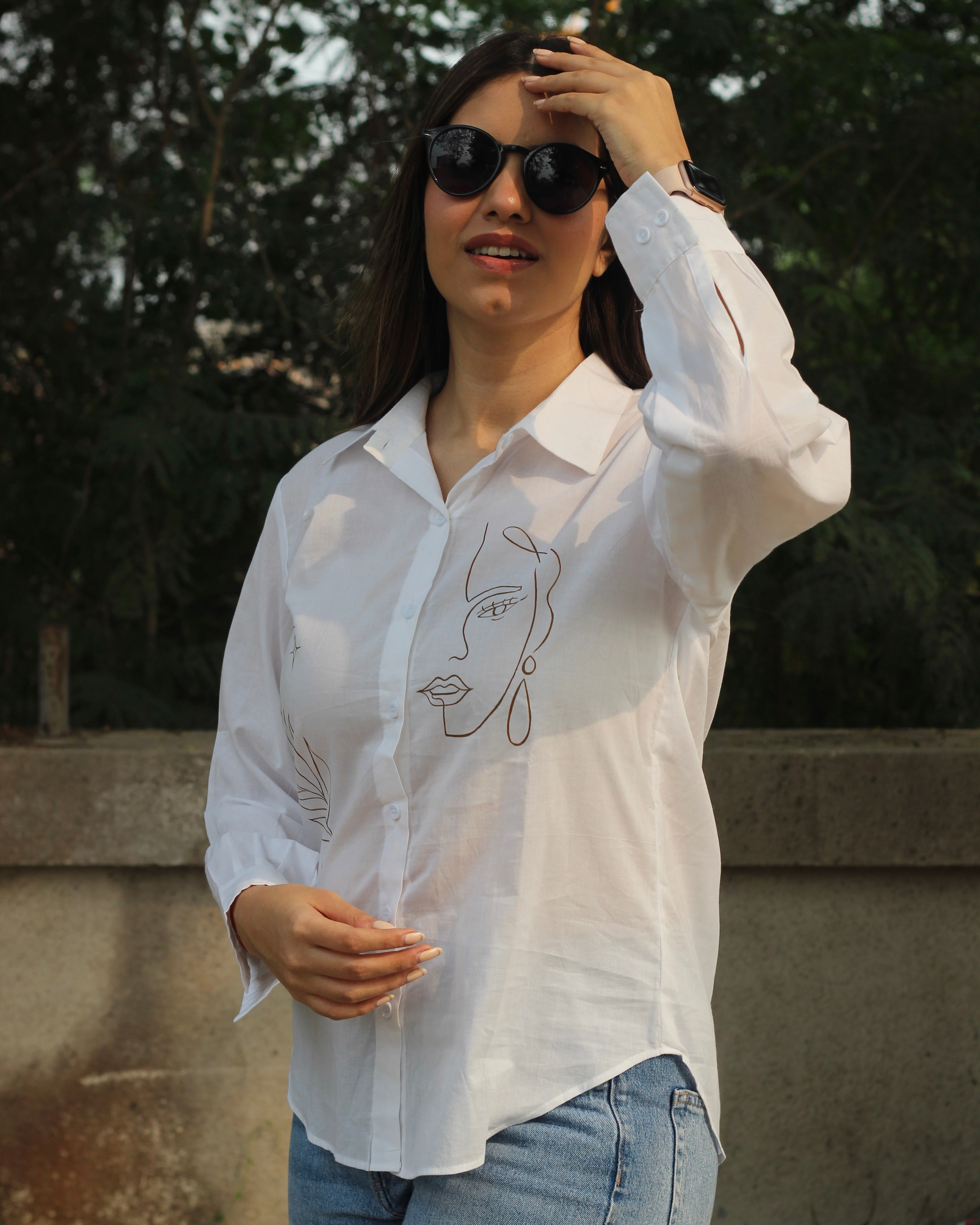 Hand-painted white shirt with bohemian brown leaf motifs, paired with jeans for a stylish look.
