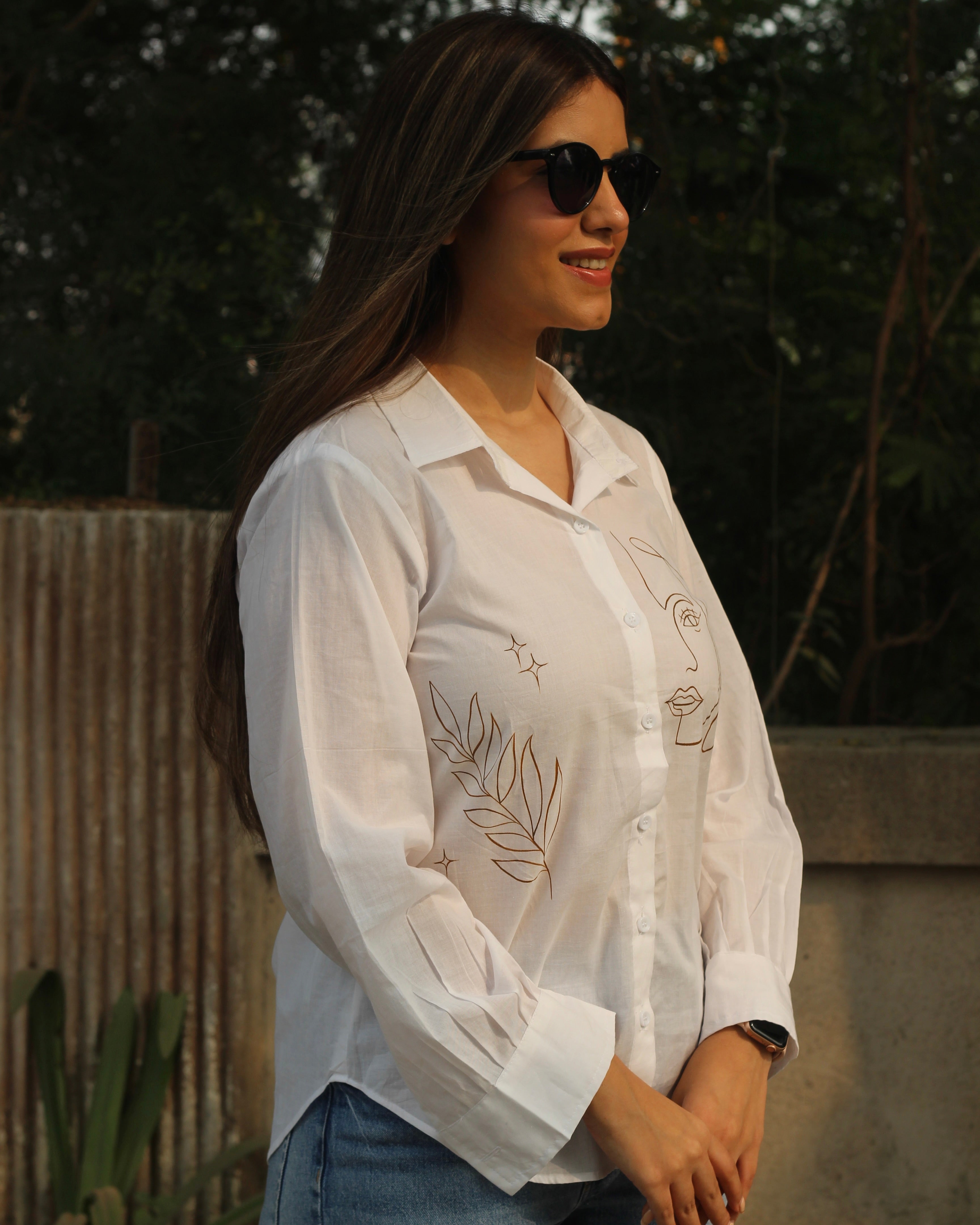 Hand-painted white shirt with bohemian brown leaf motifs, paired with jeans for a stylish look.