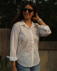 Hand-painted white shirt with bohemian brown leaf motifs, paired with jeans for a stylish look.